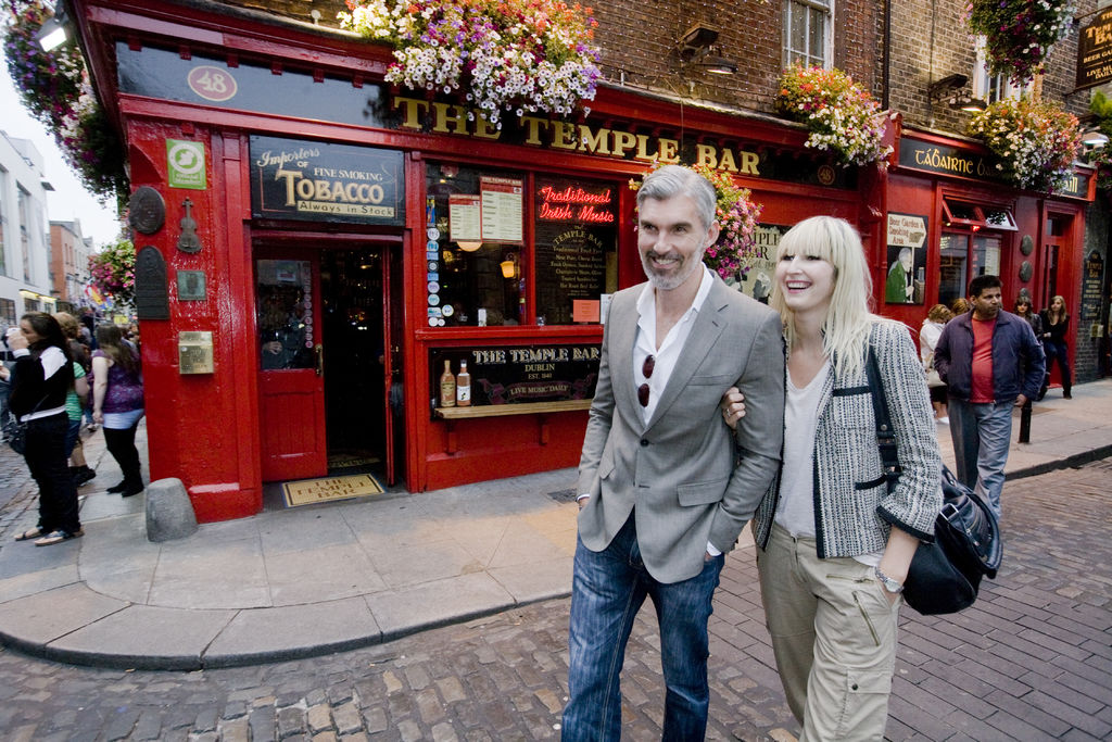 couple walking down city streets in front of pub